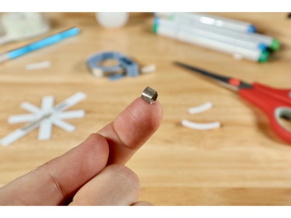 Cut a small piece of Maker Tape about 1/2" long. Then peel and roll it into a small sticky-side-out tape loop.