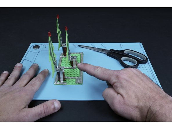 Measure, cut, peel and stick tape paths that lead from the ends of the existing left LED leg paths, down their respective trunks and to their corresponding short segments from the previous step.