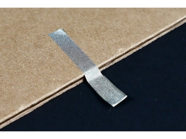 Wrap it around the end of the paper or cardboard so tape is on both sides.