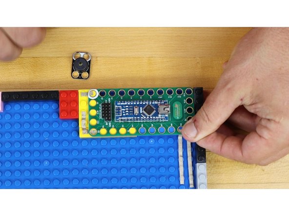 Press the Robotics board onto LEGO bricks over the Maker Tape.