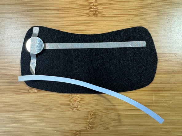 Add a long piece of Maker Tape on top of the battery as shown. Leave the backing on the tape tail for now so it doesn't curl up.