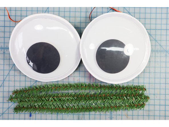Glue evergreen pipe cleaners around the eyes as shown.