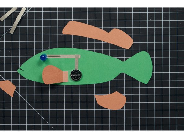 We won’t add our battery yet, but you can put it in place so we know where the pectoral fin needs to go. The fin will connect the circuit and also be used as the battery cover.