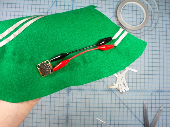 Attach a short alligator clip to the battery holder + and - holes and to each of the two Maker Tape pieces. Make sure you get the polarity correct.