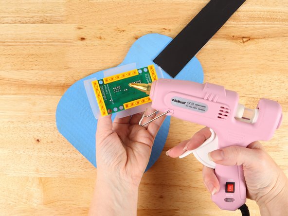 Using hot glue or another strong glue, attach the LEGO plates to the body of the guitar.