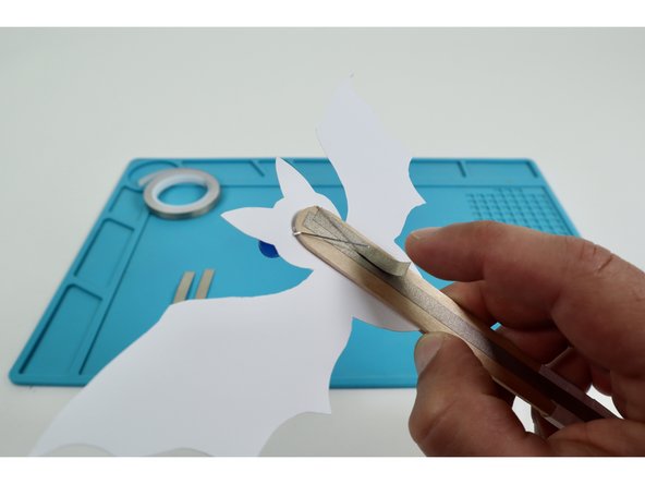 Using two of  your three Maker Tape pieces, stick one atop each of the two LED legs bent flat in the previous step. Press them into contact with the upward-facing long handle path.