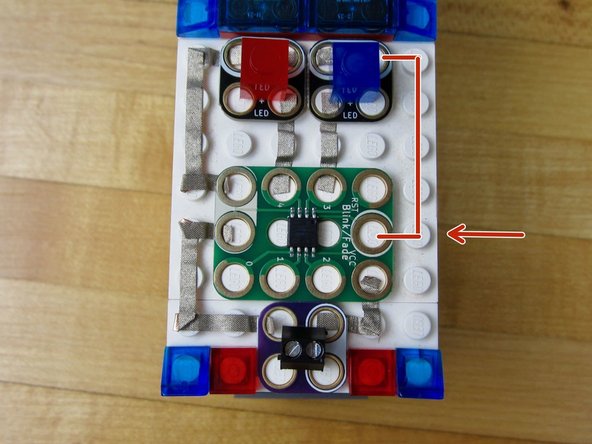 Use a longer piece of tape to go from either of the LEDs to one of the Ground holes on the Blink/Fade Board.