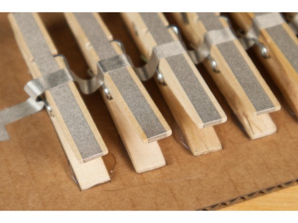 Attach the clothespins to the board in a row. Hot glue works well to hold them down.