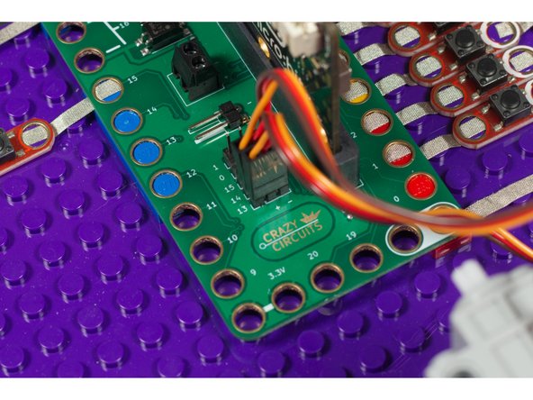 Make sure the brown wire of the servo connector is plugged into the - (negative) row and the red wire of the servo is plugged into the + (positive) row. The orange wire will be closest to the 14 or 13 numbering on the board.