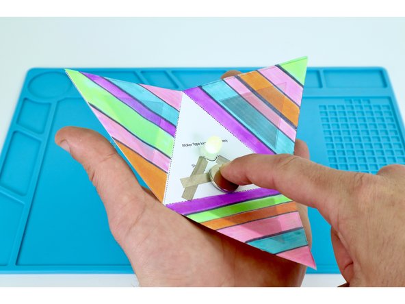 To complete the circuit and turn your LED on, peel and stick the final remaining Maker Tape section where shown in photos 2 and 3.