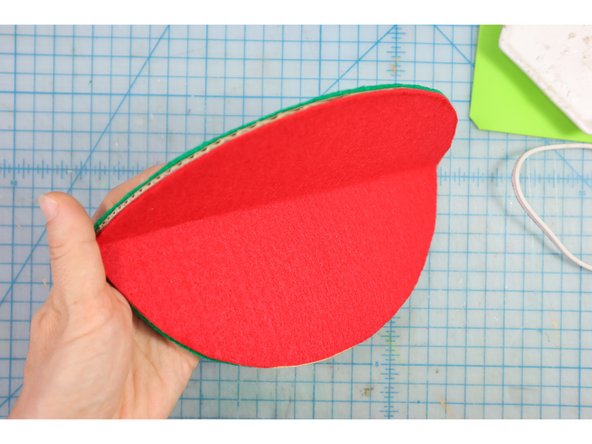 Glue the green felt pieces to the other side of the cardboard. One of the green pieces should be glued down completely. The other should only be glued around the round edge, creating a &quot;pocket&quot; to insert the popsicle stick into later.