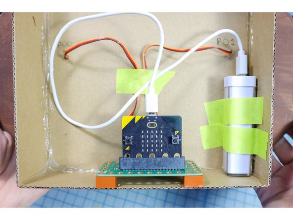 To power the fish, tape a small USB battery pack inside the fish plaque and plug in the micro:bit.