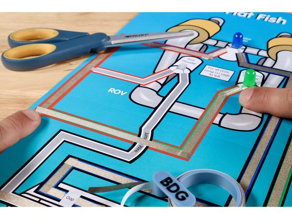 The next Maker Tape path must jump OVER the Blue LED path without touching it. Use extra length when measuring to create the necessary slack to avoid contact with the path below.
