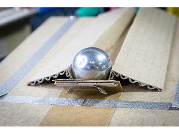 Fold the ends of a short piece of Maker Tape over so that they don't stick. Stick it underneath the bridge as shown.