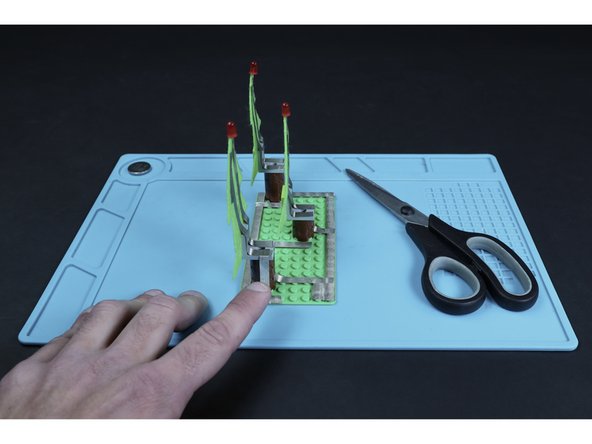 Measure, cut, peel and stick tape paths that lead from the ends of the existing left LED leg paths, down their respective trunks and to their corresponding short segments from the previous step.