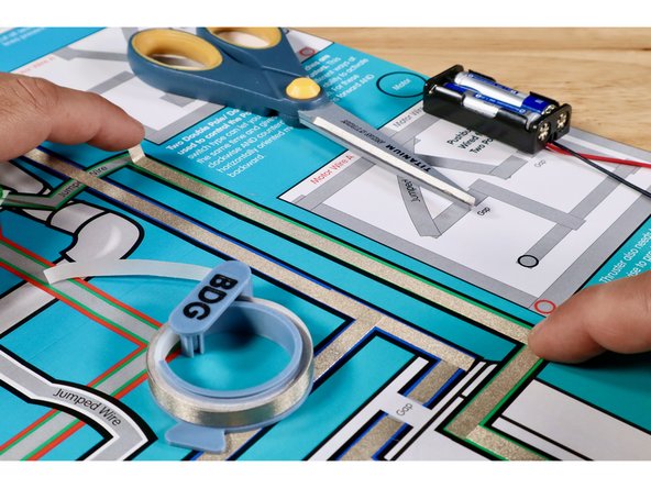 To prepare the Green LED, first orient the legs so that the Long Positive (+) Leg is on the left. Next, fold the legs flat and then in a &quot;V&quot; so that it can sit in position atop the poster. NOTE: This step is not pictured. Use the same process used to prepare the Blue LED for this LED in ITS location.