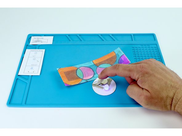 To complete the circuit and turn your LED on, peel and stick the final remaining Maker Tape section where shown in photos 2 and 3.
