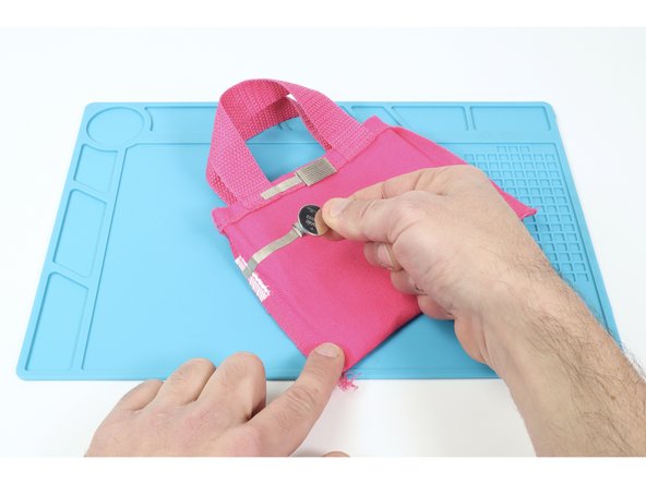 Stick a CR2032 battery positive (+) side UP atop the remaining lower tape loop. Then measure, cut, peel and stick a final Maker Tape path connecting the top of the battery to the Maker Tape path above the battery as shown.