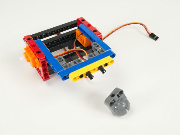 Add two black pins onto the shorter beam, in the third hole from each end.