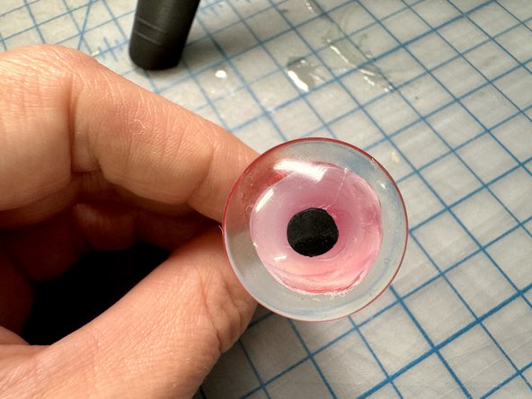 Use a very small amount of hot glue to glue it to the front of the dome.