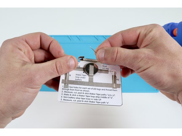 Apply a bit of hot glue to the back of the upper tab and carefully press the safety pin into it as pictured, allowing the glue to harden.