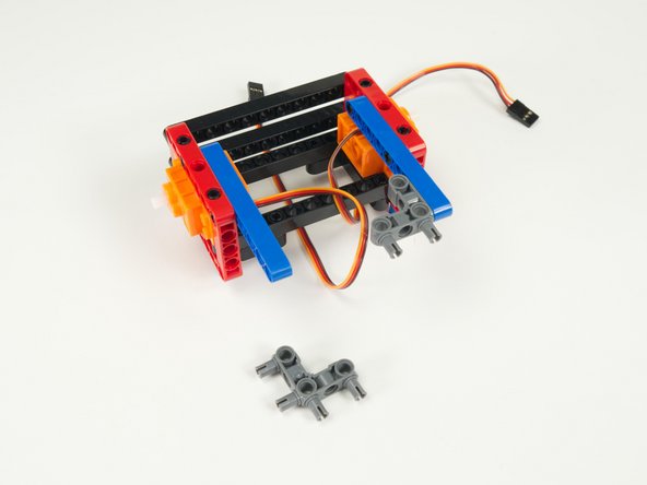 Add the two gray 90 degree connectors to the blue rear stabilizer beams as shown so the pins are facing towards the rear of the rover.