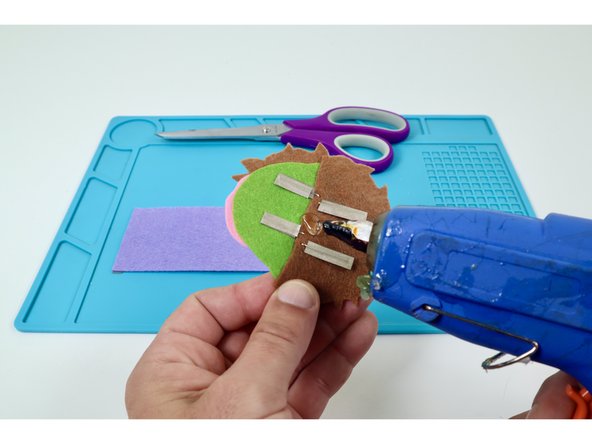 Use a small dab of hot glue where shown on the embellishment to help you stick it in the middle of the band. 