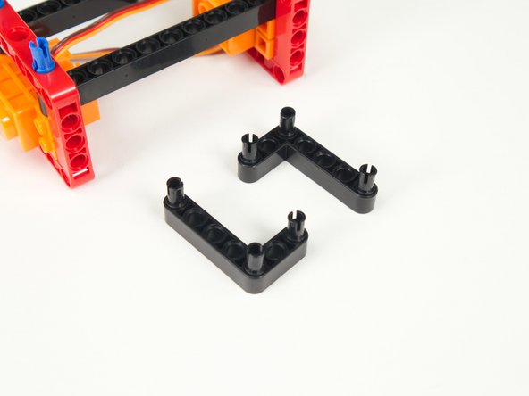 Place pins at the ends and the corner of the two black L-shaped beams as shown.