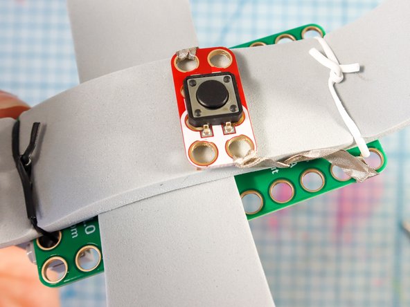 Adhere the button inside the hat where it touches the top of the head. This button will activate the code when the hat is placed on the wearer's head.