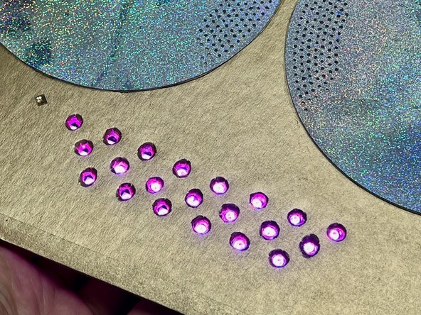 Use strong tape or hot glue to position and attach the LEDs (and the cardboard they are glued to) behind the holes.