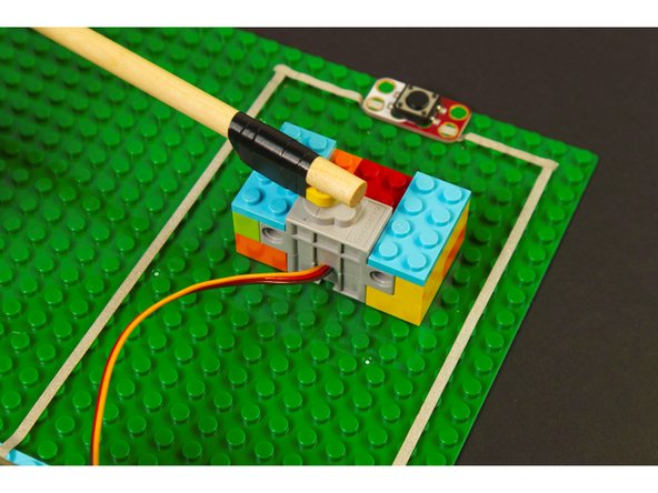 We connected a LEGO Beam 5 x 0.5 with Axle Holes on each end (11478 / 44864) to our mallet handle with a bit of electrical tape and then stuck it on our servo.
