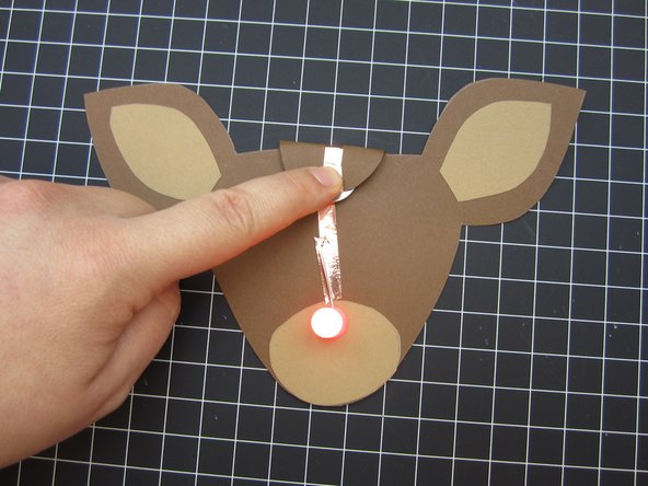 Fold down the bulb on the back so that the Positive line of tape make contact with the top of the battery.