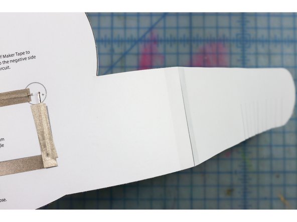 Tape the headband pieces to the sides of the paper as shown. One side's fringe will face up and the other will face down so that you can interlock them as shown.