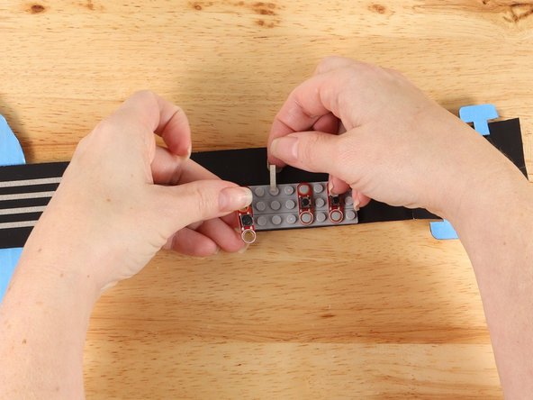 Lift up the second button and use a small piece of Maker Tape to start a path straight out from the button as pictured. 