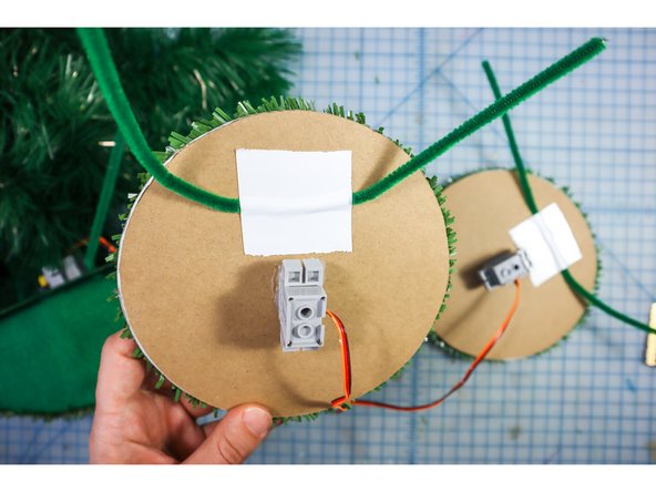 Use duck tape to tape a pipe cleaner to the back of the eyes as shown. This will allow you to attach the eyes to the branches of the tree.