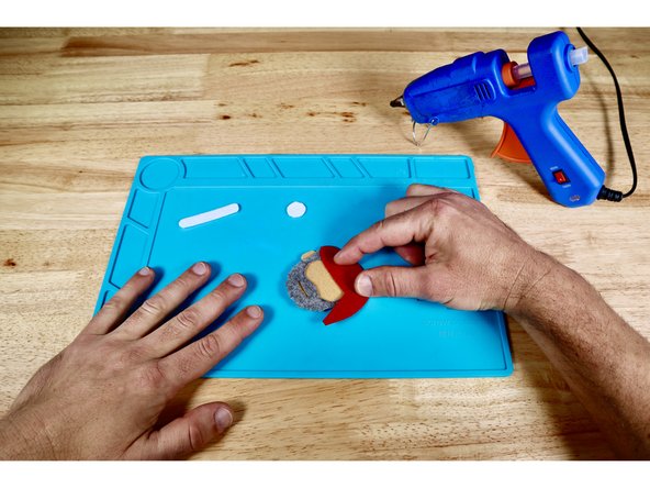 Press the hat into place atop the hot glue as shown.