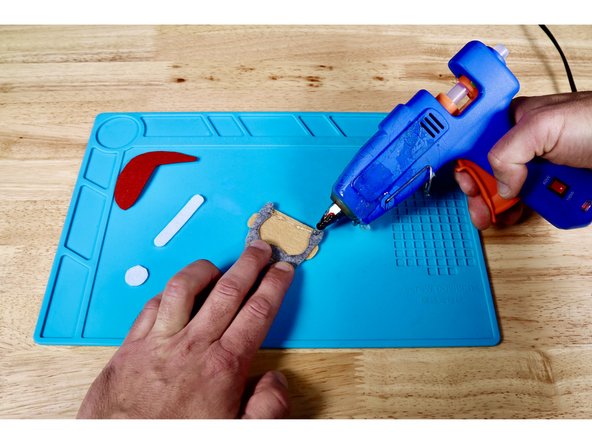 Using a hot glue gun and photo one for reference, squeeze a bead of hot glue across the upper edge of the head.