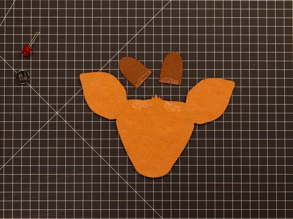 On the back side add a bit of glue to the area where the antlers will go. Add a bit of glue to the bottom of the antlers as well.