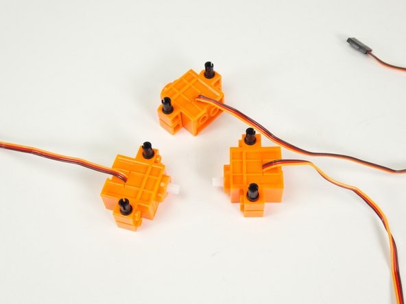 With the wires of the servos facing up, add the black pins as shown.