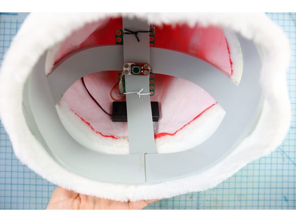 Insert the rest of the assembly inside the hat. It's easiest to do this in two steps: detach the foam piece and place it inside, then place the headpiece inside, then carefully re-attach the stick to the motorhead inside the hat.