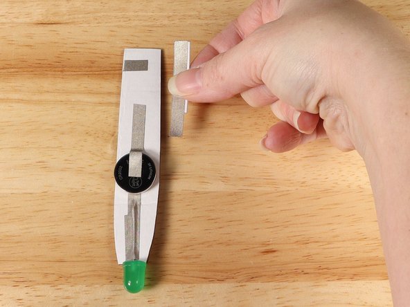 Add the paper switch to the end of the path coming from the battery. The other end of the switch should come in contact with the strip of Maker Tape that wrapped around to the front from step 11.