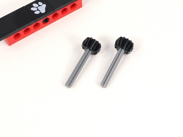 Add a small black gear to an axle with end stop and push it all the way down to the end stop. You will need two of these.