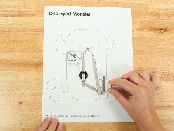 Add four small pieces of double-sided foam tape to the squares around the outline of the monster.