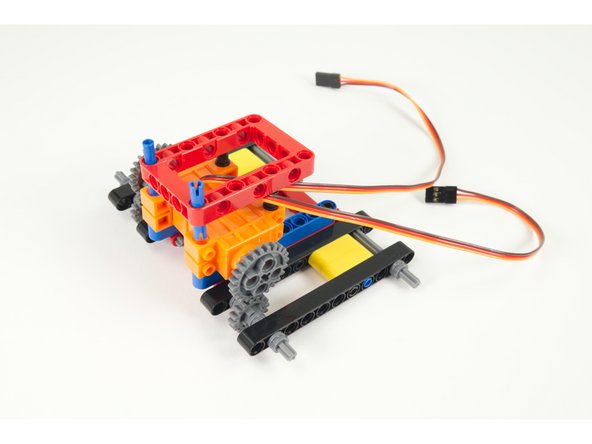 Press the top frame in place so the longer pins go into the holes on the front of the servos and the pins already in the back half of the servos go into the holes at the back of the frame.