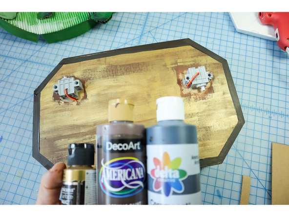 Paint the plaque medium brown, then use gold paint to dry brush over it. Finally, create a border with dark brown.