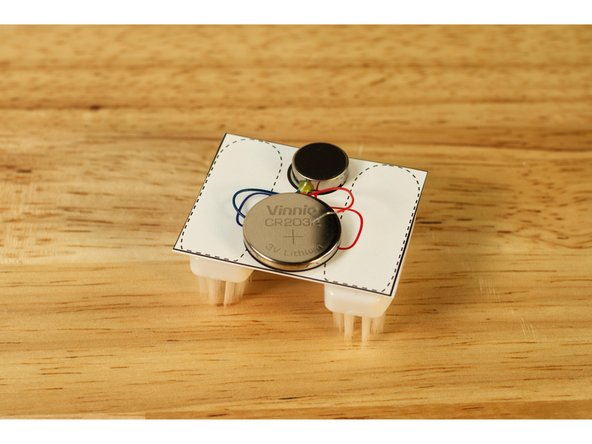 Press the battery against the tape, so the positive side (marked with a + sign) is facing up.