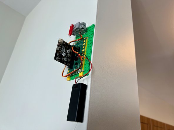 Tape the other end of the fishing line to the wall on the other side of the room. There should be about 3 inches of slack left in the line to allow the motor to move.