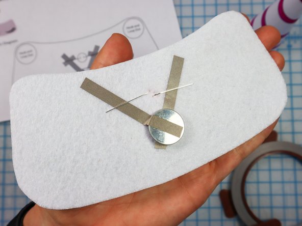 Fold each LED leg down flat against the felt, making sure the longer, positive leg touches the piece on the left, and the shorter, negative leg touches the piece on the right.