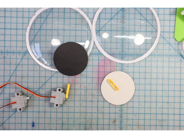 Reuse the googly eye pupils, and glue the motorheads to the back, positioning the &quot;+&quot; a bit away from the edge.