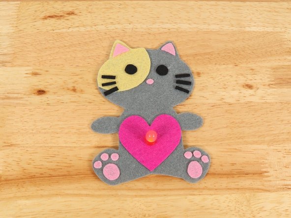 To make the Cat look like it is holding the heart, fold the paws inward and keep them in place with a small amount of hot glue.